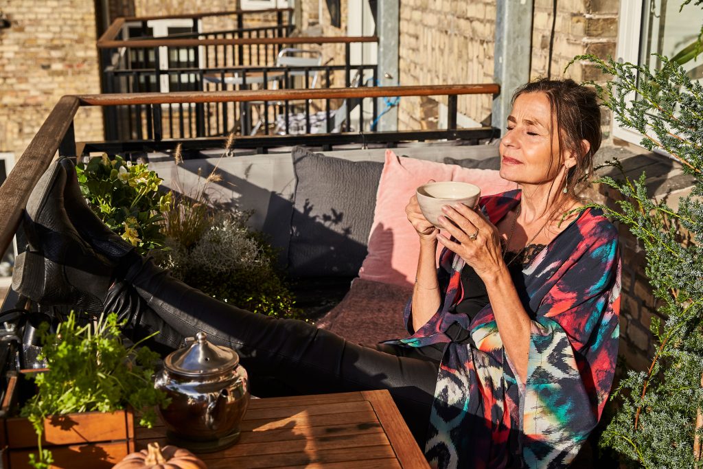 Lea, der nyder solen og en kop kaffe på sin altan
